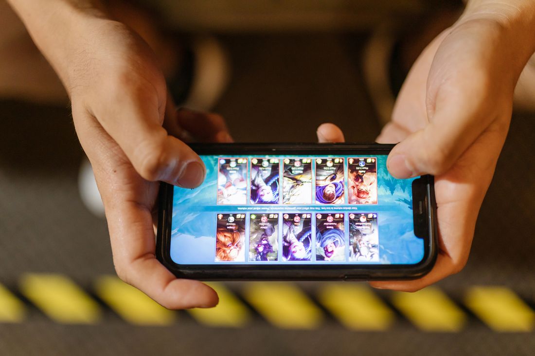 Seseorang bermain game di ponsel cerdas sambil bersantai